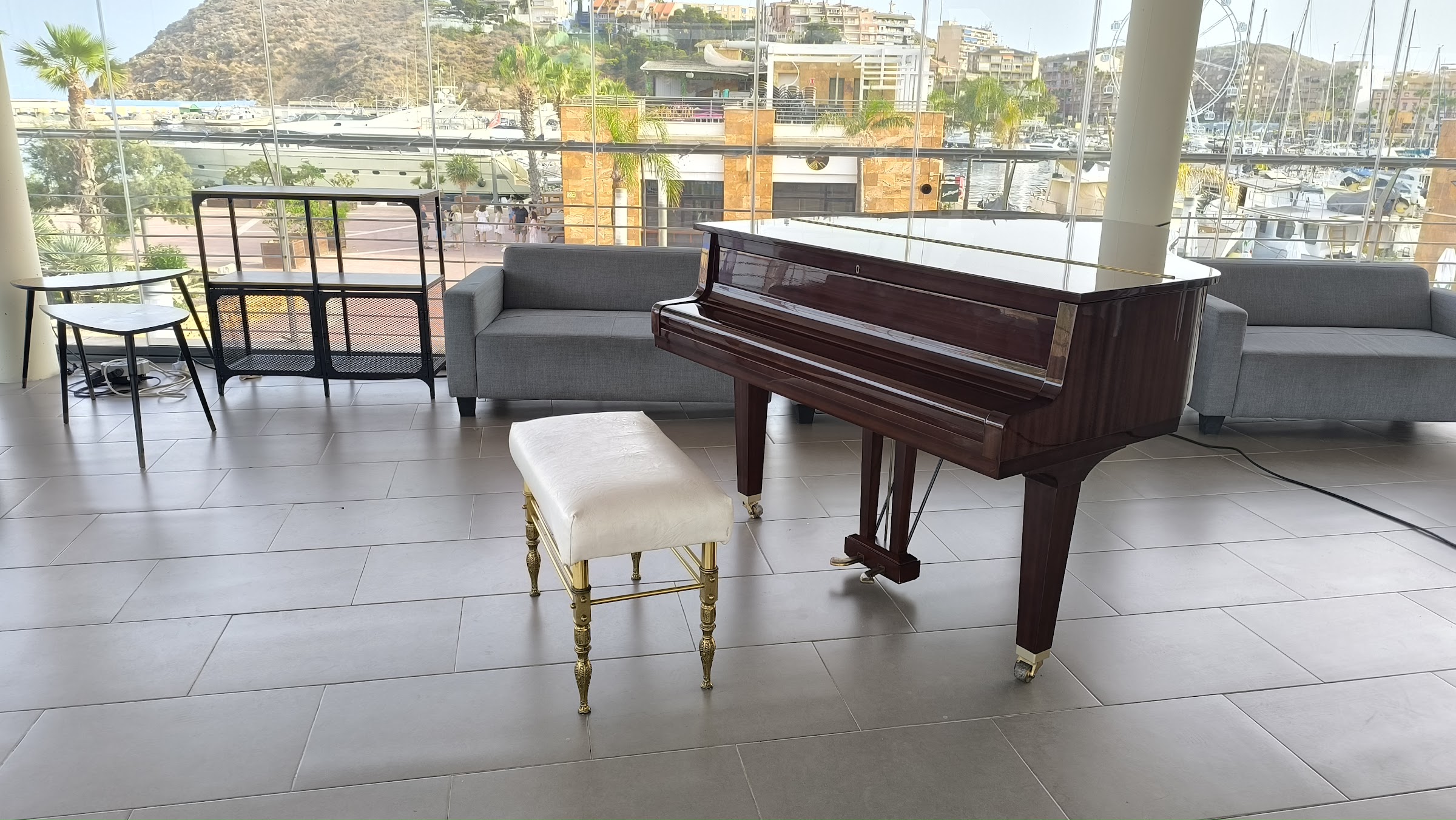 Sala de Mazmara Sunset con el piano frente a los ventanales y el puerto deportivo de Mazarrón al fondo