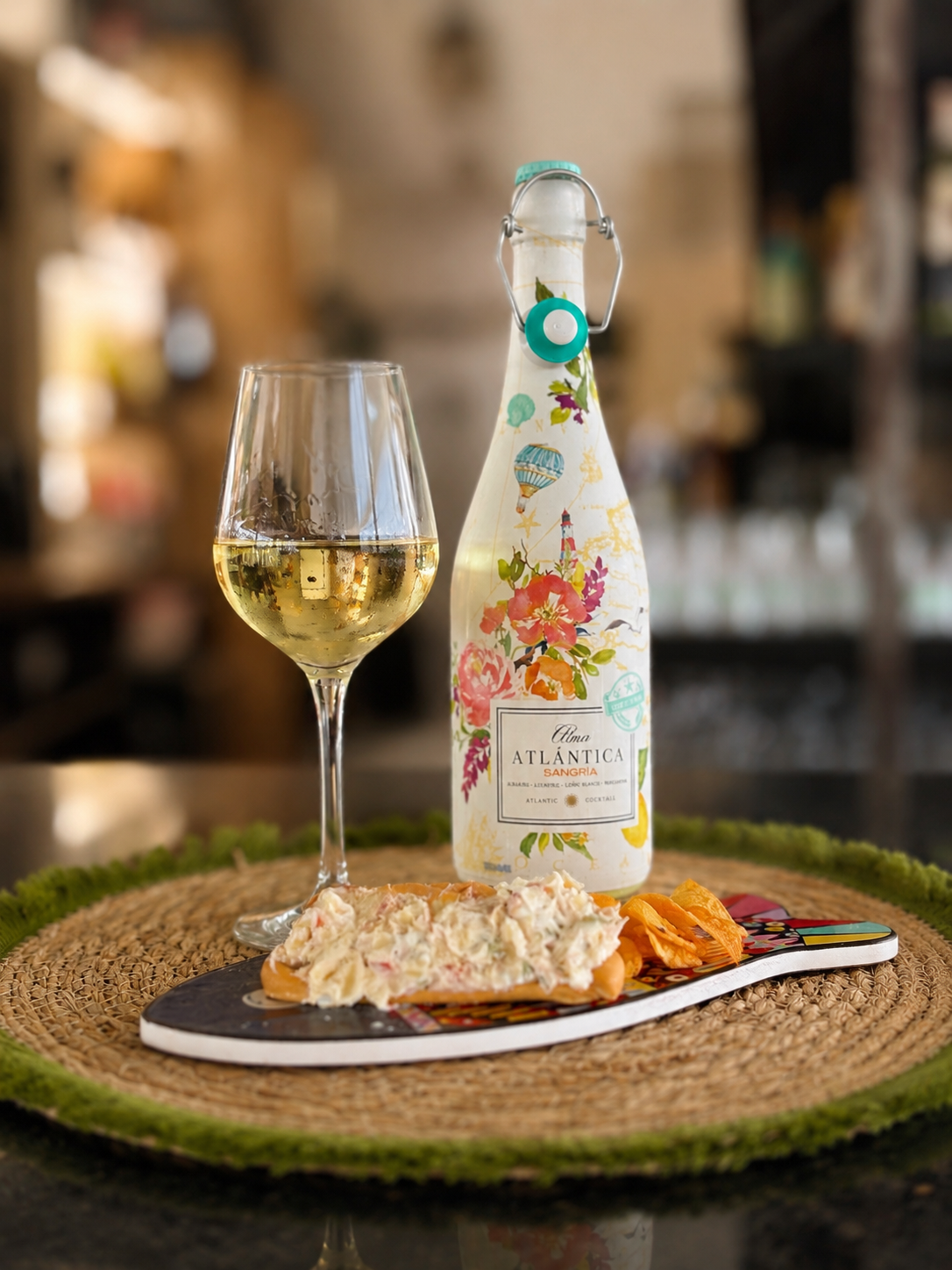 Botella de sangría y copa de vino blanco junto a una marinera y patatas