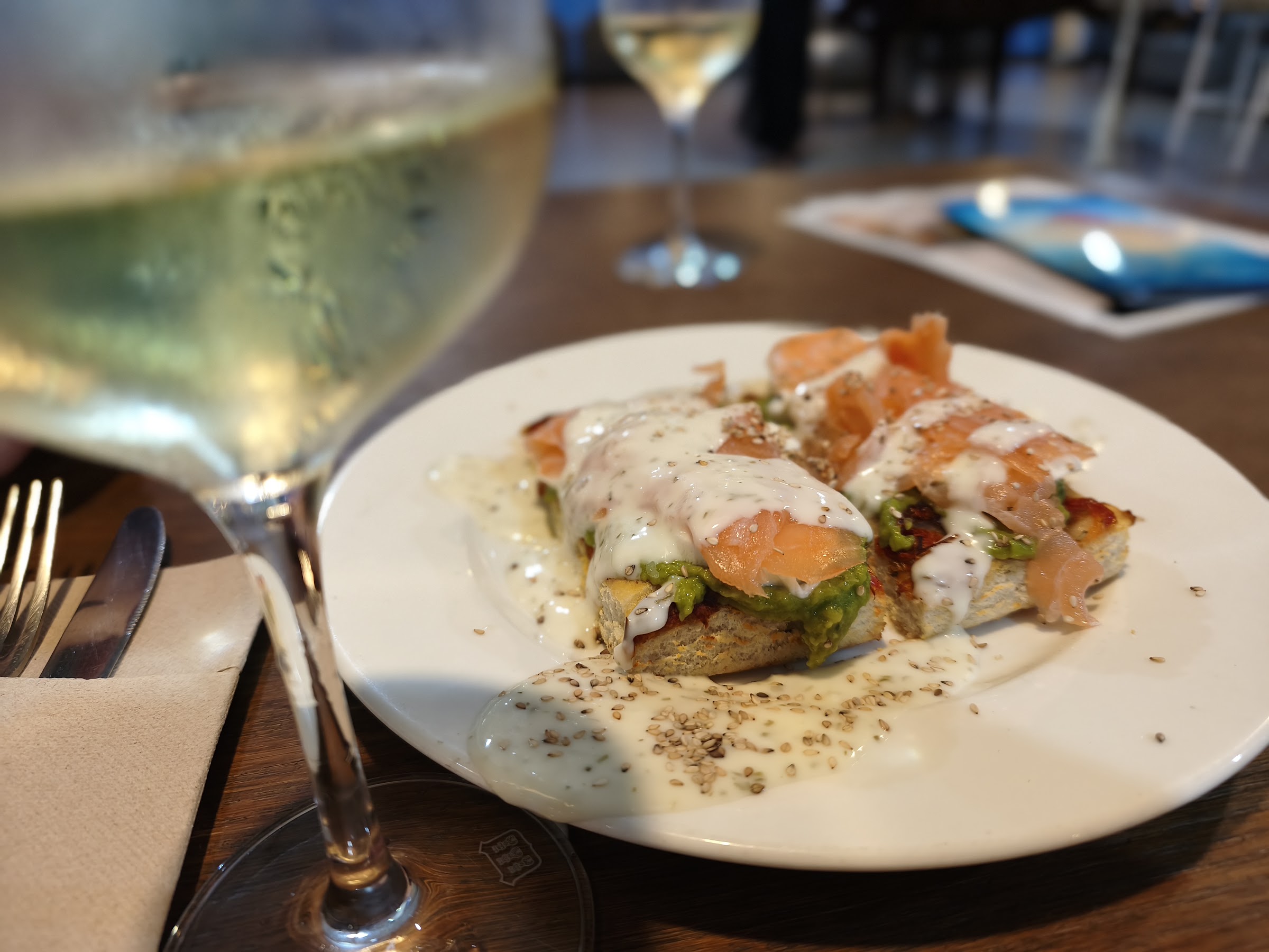 Tosta de salmón y aguacate con una copa de vino blanco